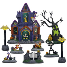 Halloween village decoration with purple house, jack-o'-lantern figures, and a bat-wing tree display
