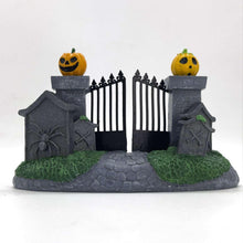 Halloween village decoration with two jack-o'-lantern posts, black fence, stone base, green grass