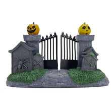 Halloween village decoration with gray fence, two pumpkin posts, stone path, and green grassy mounds