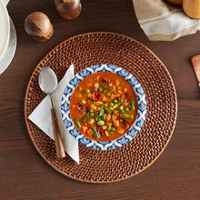 Woven placemat with a blue patterned paper bowl of soup with peas