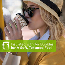 Insulated paper cup with beige and green swirl pattern, held to lips for sipping