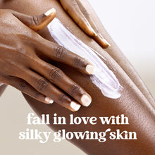 Hand applying white body scrub for silky, glowing skin.