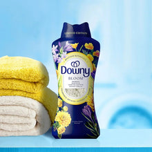 Downy Bloom limited edition scent booster beads pouch beside folded towels.
