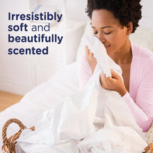 Woman holding white dryer sheets while folding bedding