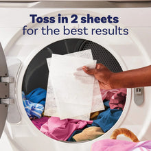 Laundry dryer with white dryer sheet being placed among clothes