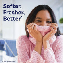 Woman holding a pink dryer sheet to cover her nose and smell it