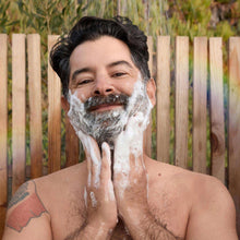 Man washing with soap foam on face and chest outdoors