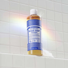 Liquid soap bottle with white cap inside a shower with foam