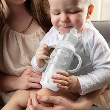Anti-colic baby bottle held by an infant, clear nipple and gray handle