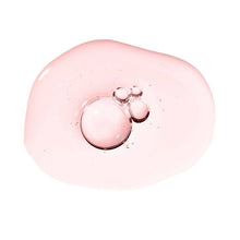 Pink glossy facial oil swatch with two small droplets on a white background.