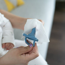 White wipe cleaning a blue pacifier held between hands.