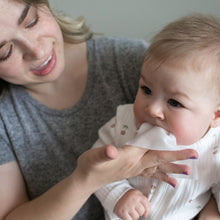 Caregiver applying a nose and face wipe to a baby’s cheek and mouth