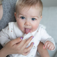 Baby sticks out tongue while caregiver wipes with a nose and face wipe