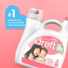 Baby liquid laundry detergent bottle with pink label and red cap against a pink backdrop
