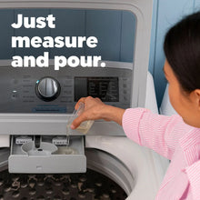 Baby liquid laundry detergent being poured into an open washing machine detergent area