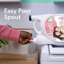 Baby liquid laundry detergent bottle pouring from a spout into a clear cup