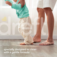 Baby liquid laundry detergent bottle and child wearing pajamas standing on a floor