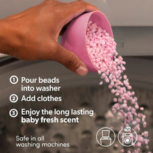 Pink laundry scent booster beads being poured into a washing machine