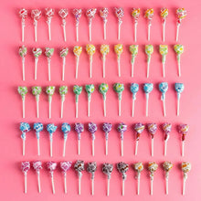 Rows of Dum Dums lollipops on white sticks, assorted wrapper colors