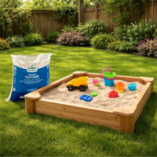 Washed play sand bag beside wooden sandbox with colorful toy accessories