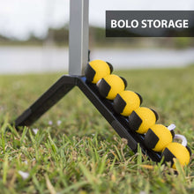Yellow beanbag-style ladderball balls on black thrower rest in grass