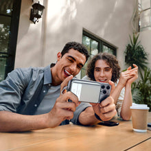 Power bank powering two smartphones as two people use phones at a café table