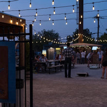 Warm white cafe string lights stretched across an outdoor market walkway