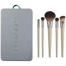 Makeup brush set with four brushes standing beside a gray case with handle, tan bristles