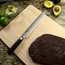 9-inch hollow-edge slicer knife with perforated blade on wooden cutting board