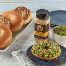 Everything bagel seasoning bottle beside bagels and a green topping