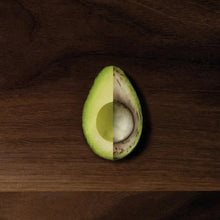 Vacuum-sealed avocado half on dark wooden surface.