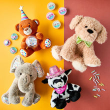 Gray plush elephant toy among other plush animals, wearing a colorful bib.