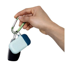 Silicone straw carrying case with blue lid and metal carabiner, held by hand