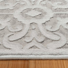 Close-up of light gray area rug with scrolling damask motif and plush pile