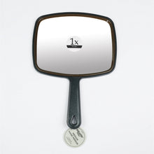 Black 1x face mirror with rounded frame, long handle, and suction base.