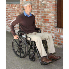 Black folding wheelchair with armrests and footrests while seated outdoors