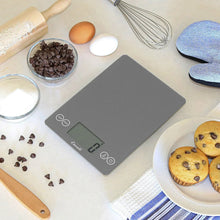 Digital kitchen scale with LCD screen and bowls of baking ingredients nearby