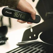 Infrared thermometer in hand with LCD temperature readout and folding probe