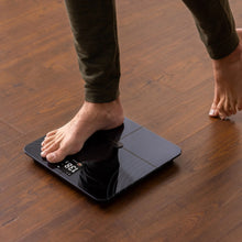 Smart fitness scale under bare feet with a digital weight readout