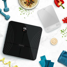Smart fitness scale and kitchen scale on a countertop with cooking ingredients around