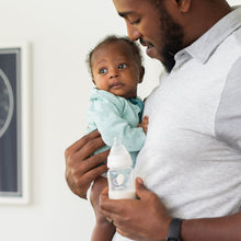 Father holding baby with clear standard-neck bottle and white nipple