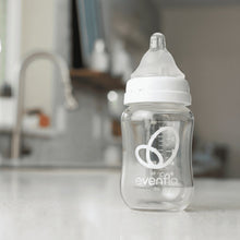 Close-up of clear glass Evenflo bottle with white nipple and measurement markings