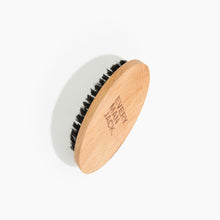 Men's beard brush with a light wooden back and dark bristle head
