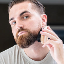 Men's beard brush held to a man’s beard for grooming