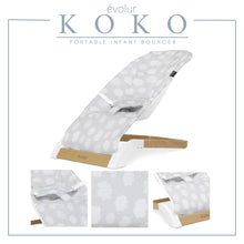 Portable infant bouncer with light gray cloud-pattern seat on white frame and wood-accent base