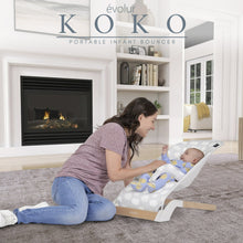 Portable infant bouncer with light gray cloud-pattern seat and baby, white frame