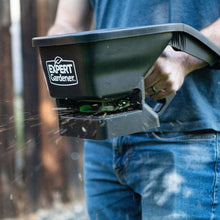 Expert Gardener handheld spreader dispensing through green opening