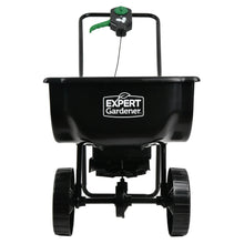 Black push broadcast spreader front view with hopper, wheel set, and Expert Gardener logo