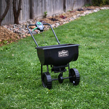 Black push broadcast spreader with hopper, wheels, and Expert Gardener label