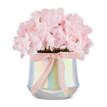 Pink hydrangea flowers in iridescent ceramic pot with pale pink ribbon bow